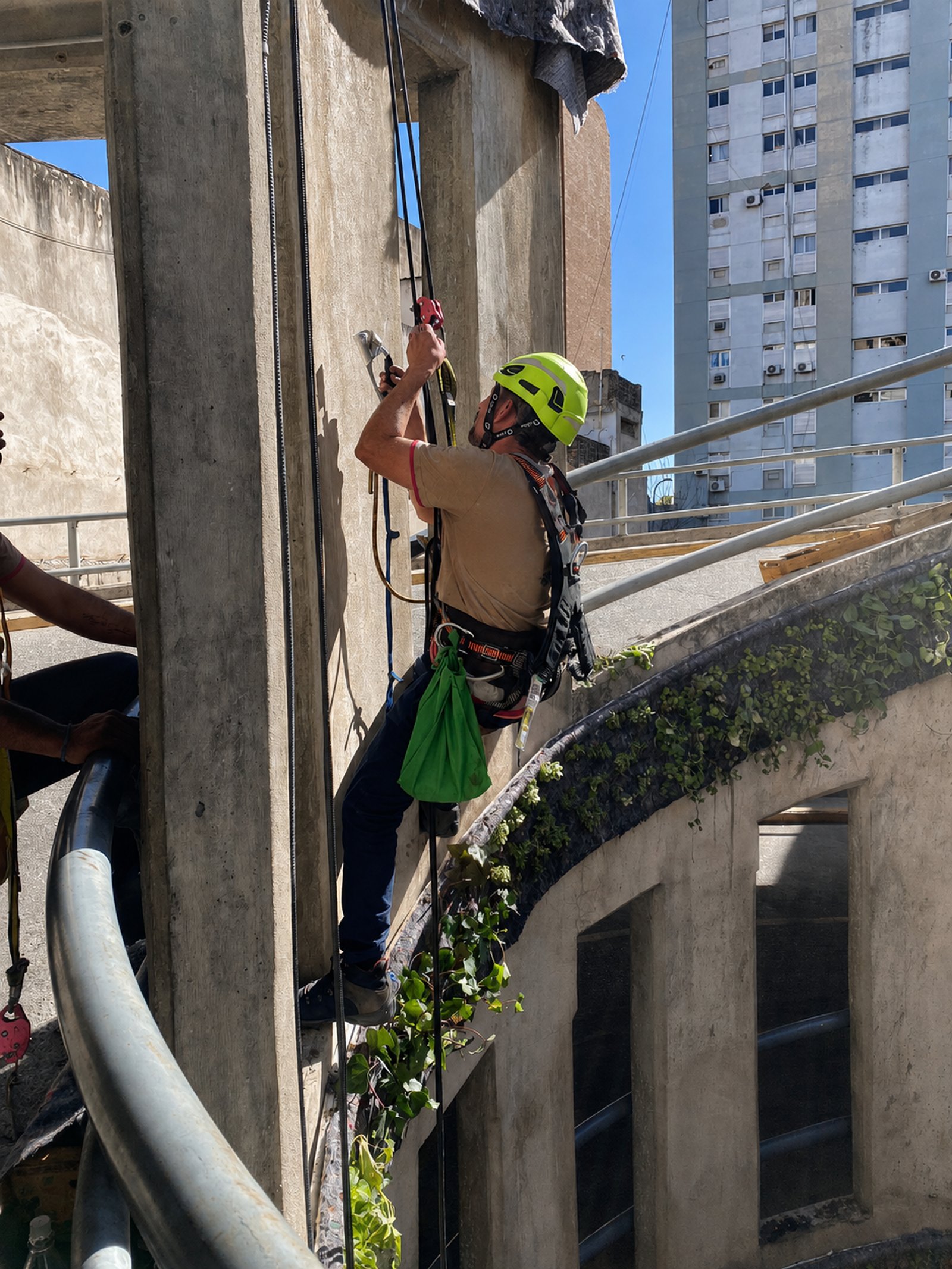 Pessoa em rapel descendo fachada de prédio de concreto aparente — projeto Parking Oulton :: Córdoba :: Jardín Vertical :: Diseño y construcción STIPA Arte, por STIPA Arte Natural, 